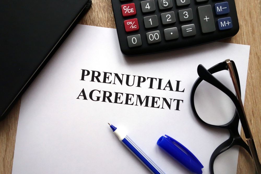 prenuptial agreement next to a calculator, pen, and glasses